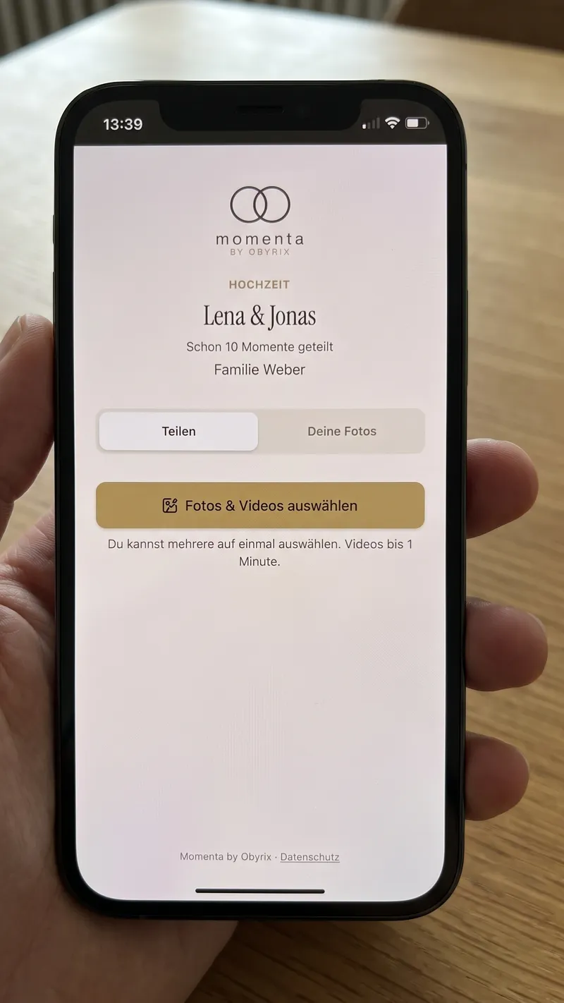 Hand hält ein iPhone mit der Momenta-Gäste-Seite zum Event Lena & Jonas